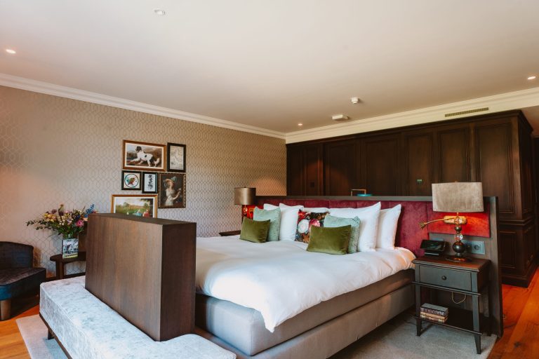Suite van The Duke met tweepersoonsbed, groene sierkussens, houten wandpanelen en ingelijste kunst aan de muur