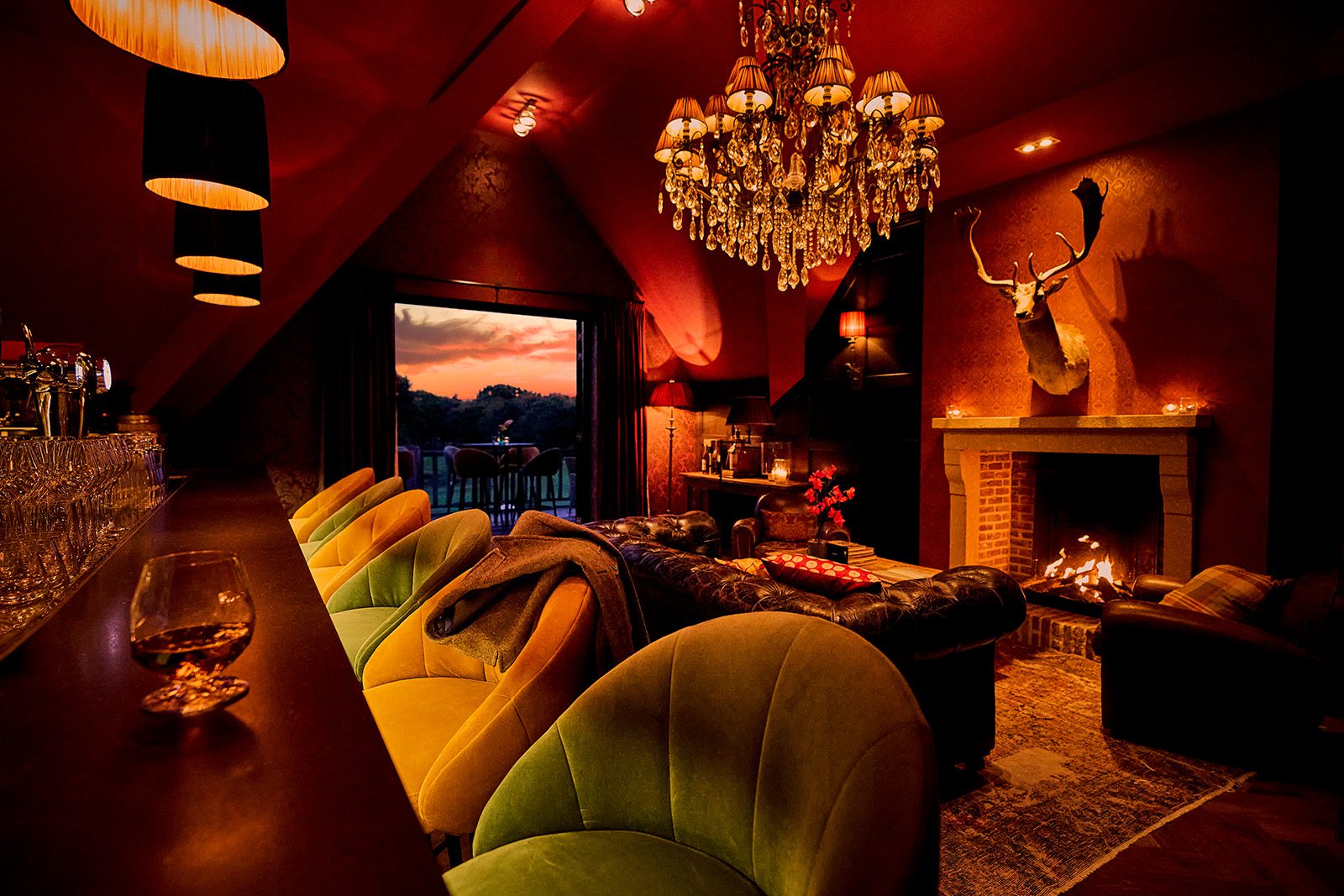 The Whiskeyroom met groene barkrukken, leren banken, een brandende open haard en een kroonluchter